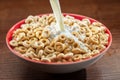 Pouring milk into the bowl with corn snacks. Fast cereal breakfast. Close-up Royalty Free Stock Photo