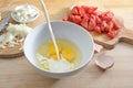 Pouring milk into a bowl with eggs, preparation for a frittata or omelet with tomatoes and onions, wooden kitchen board, selected Royalty Free Stock Photo