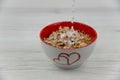 Pouring milk into a cereal bowl, on the white wood tabl Royalty Free Stock Photo