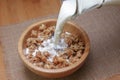 Pouring milk into cereal breakfast in wooden bowl Royalty Free Stock Photo