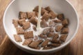 Pouring milk into chcolate cereal pillow in white bowl on table Royalty Free Stock Photo