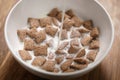 Pouring milk into chcolate cereal pillow in white bowl on table Royalty Free Stock Photo