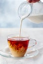 Pouring milk into cup of black tea on white wooden table Royalty Free Stock Photo