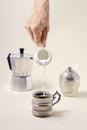 Pouring milk in  cup of coffee, geyser coffee maker and shugar Royalty Free Stock Photo