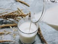 Pouring milk in the glass on blue background. Fresh milk pouring making a crown splash. Front view. Milk glass top view. Royalty Free Stock Photo