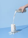 Pouring milk into the glass on a blue background. Spilled milk on the table Royalty Free Stock Photo