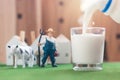 Pouring milk in glass with Miniature Farmer and cow figure model on Simulation grass