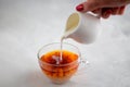 Pouring milk from the jug into a cup of black tea Royalty Free Stock Photo