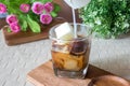 Pouring milk from a jug to a glass of espresso ice cubes. Cold drink iced coffee with frozen milk. Iced coffee in a tall glass wit Royalty Free Stock Photo