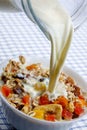 Pouring milk over muesli with dried fruit Royalty Free Stock Photo