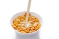 Pouring milk in a white bowl with corn flakes on white background Royalty Free Stock Photo