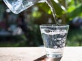 Pouring Mineral Pure Water into Glass on Wooden Table with Over Light Day Royalty Free Stock Photo