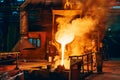 Pouring molten metal into mold from ladle container in foundry metallurgical factory workshop, iron cast, heavy