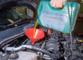 Adding motor oil to a car engine during maintenance