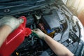 Pouring new engine oil from canister into motor funnel at car service, close up