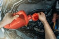 Pouring new engine oil from canister into motor funnel at car service, close up