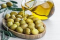 Pouring olive oil from bottle into glass on raw turkish green olives in bamboo bowl Royalty Free Stock Photo