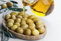 Pouring olive oil from bottle into glass on raw turkish green olives in bamboo bowl Royalty Free Stock Photo