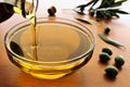 Pouring olive oil from bottle to glass bowl Royalty Free Stock Photo