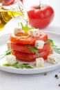 Pouring olive oil over salad with beef tomatoes and feta