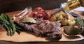 Pouring olive oil over a sirloin steak with asparagus, potatoes and roasted tomatoes