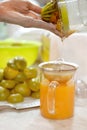 Pouring orange juice from a juicer into a glass jar.