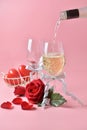 Pouring out of white wine from bottle to glass, with rose at the bottom on pink background. Concept of Valentine`s Day Royalty Free Stock Photo