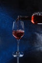 Pouring pink wine from bottle into glass on color background Royalty Free Stock Photo