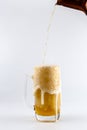 Pouring process of lager beer into a beer glass mug, splashes, drops and froth around glass mug Royalty Free Stock Photo