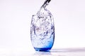 Pouring purified drinking water into a blue glass, white background carrara marble base. full glass