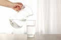 Pouring purified fresh water from the jug in glass on table Royalty Free Stock Photo