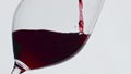Pouring red liquid glass closeup. Gourmet alcoholic drink bubbled wineglass