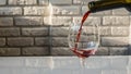 Pouring red wine from a bottle into a glass,against the background of a brick wall,close-up. Royalty Free Stock Photo