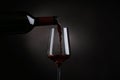 Pouring red wine from bottle into glass on black background Royalty Free Stock Photo