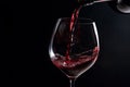 Pouring red wine from a bottle into a glass on a black background. Generative ai Royalty Free Stock Photo