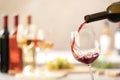 Pouring red wine from bottle into glass on blurred background. Royalty Free Stock Photo