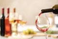 Pouring red wine from bottle into glass on blurred background Royalty Free Stock Photo