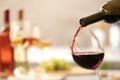 Pouring red wine from bottle into glass on blurred background Royalty Free Stock Photo