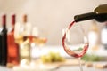 Pouring red wine from bottle into glass on blurred background Royalty Free Stock Photo