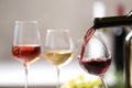 Pouring red wine from bottle into glass on blurred background Royalty Free Stock Photo