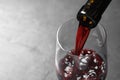 Pouring red wine from bottle into glass on grey background, closeup. Royalty Free Stock Photo