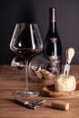 Pouring red wine in crystal glass, bottle, corkscrew, opener, sommelier knife, transparent decanter, corks, cheese on Royalty Free Stock Photo
