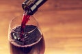 Pouring red wine into the glass against wood