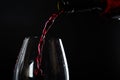 Pouring red wine with splashes and drops into a glass on a black background Royalty Free Stock Photo