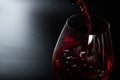 Pouring red wine with splashes and drops into a glass on a black background Royalty Free Stock Photo