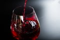 Pouring red wine with splashes and drops into a glass on a black background Royalty Free Stock Photo