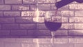 Pouring red wine into a glass,close-up,against the background of a brick wall. Royalty Free Stock Photo