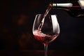 Pouring red wine into a glass on a dark background with copy space, hand Pouring red wine into a wine glass. close up, AI Royalty Free Stock Photo