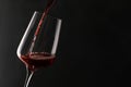 Pouring red wine into glass on dark background Royalty Free Stock Photo
