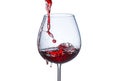 Pouring red wine into a glass with splashes on a white background close-up Royalty Free Stock Photo